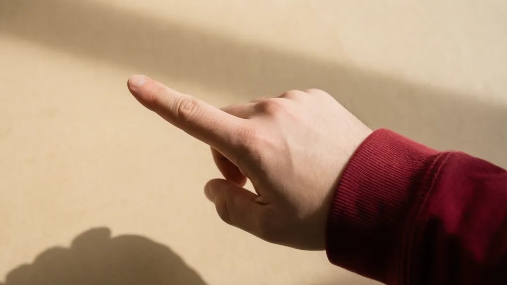 Mão com dedo indicador apontando para cima, escrevendo no ar, visto de cima.
